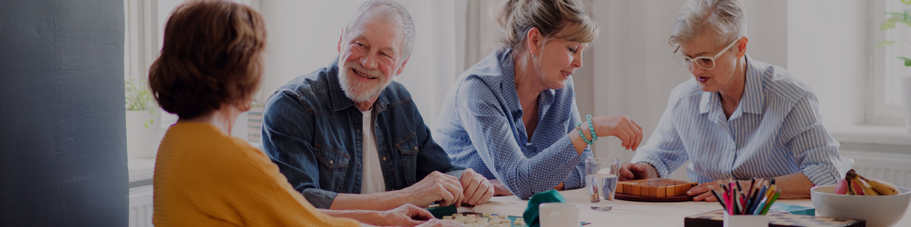 Group of mixed older adults gathered around a table for conversation and games